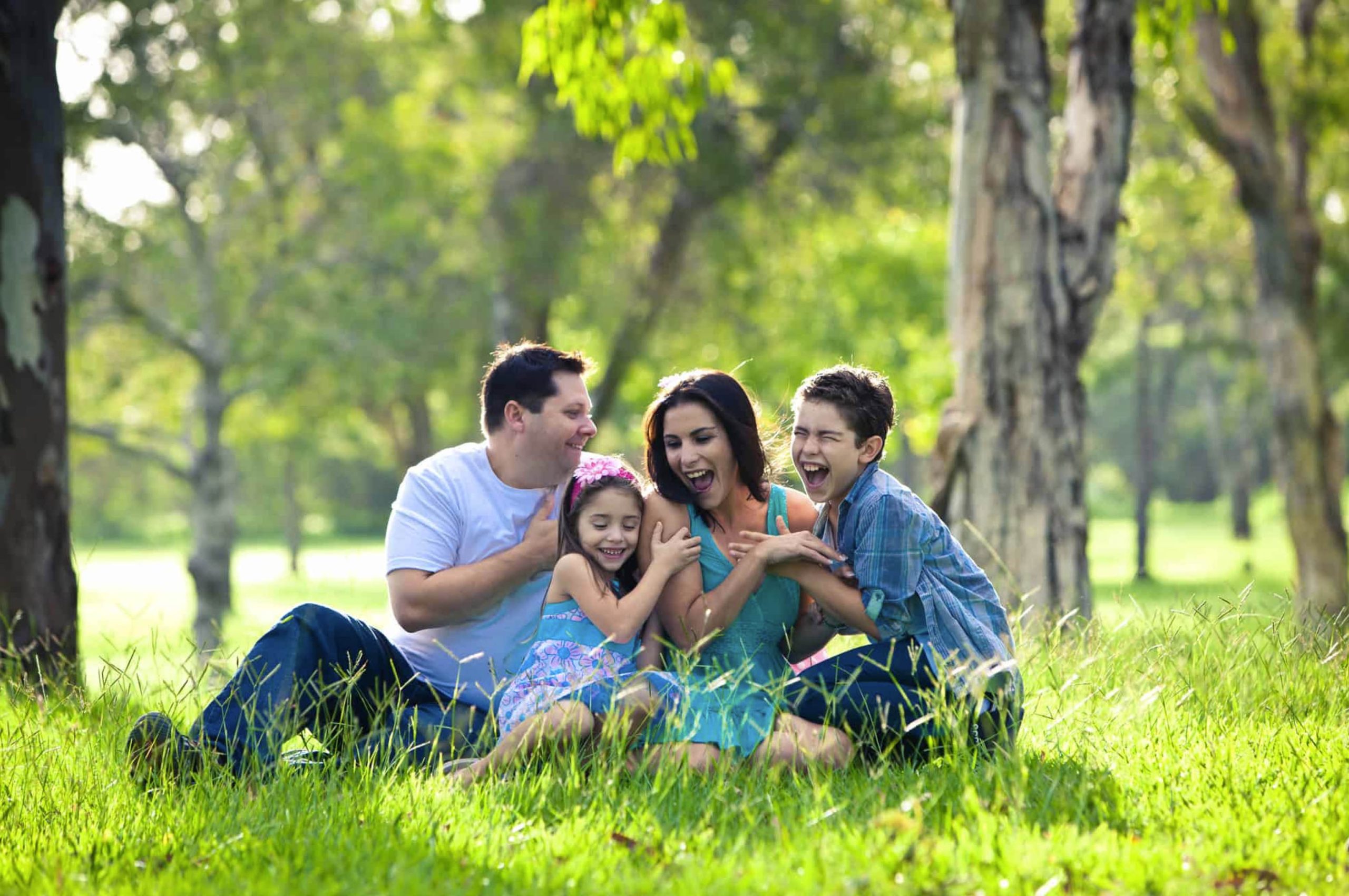 ACGrace - A family sitting on the grass in a park.