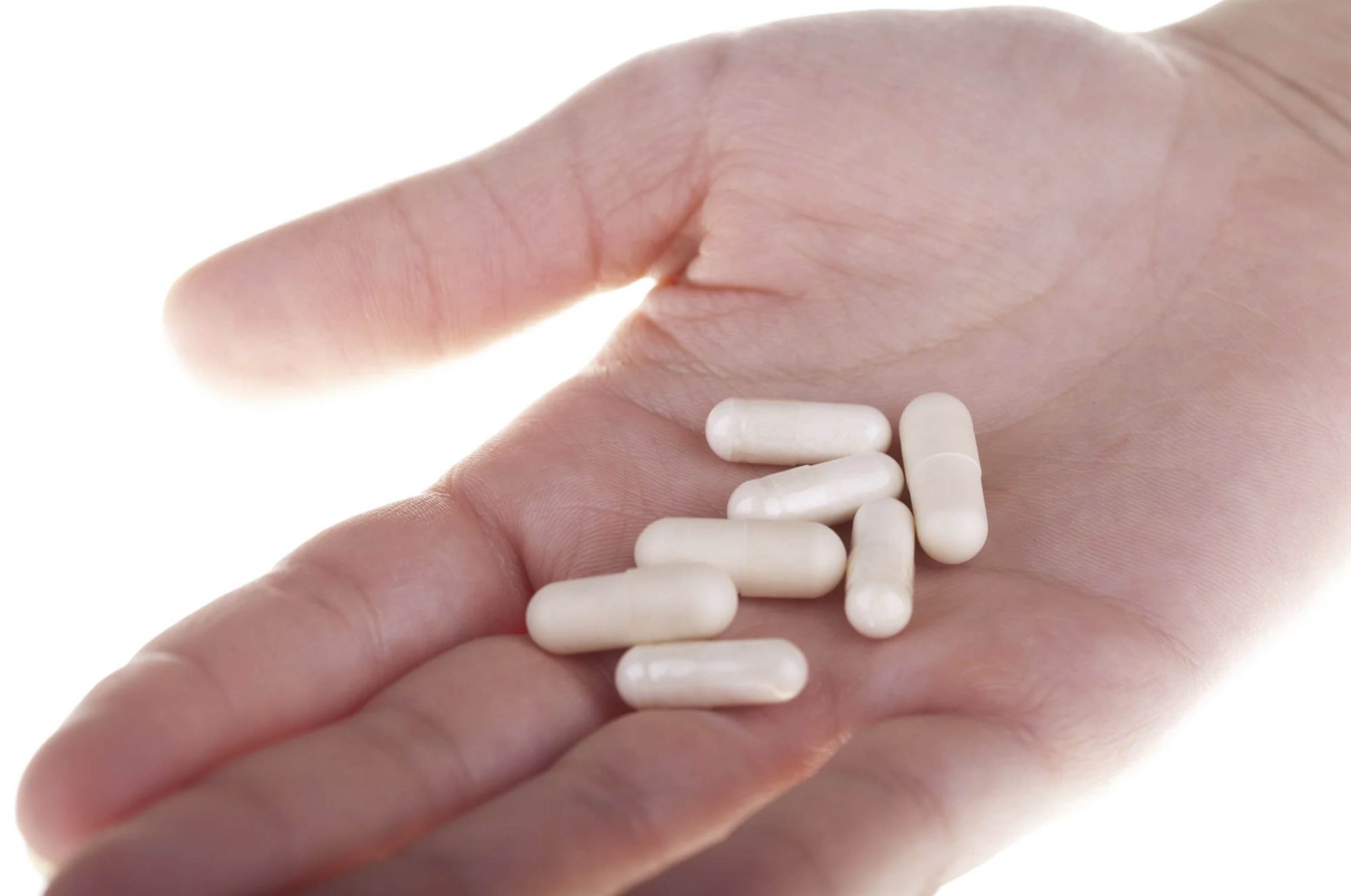 ACGrace - A person's hand holding several white pills.