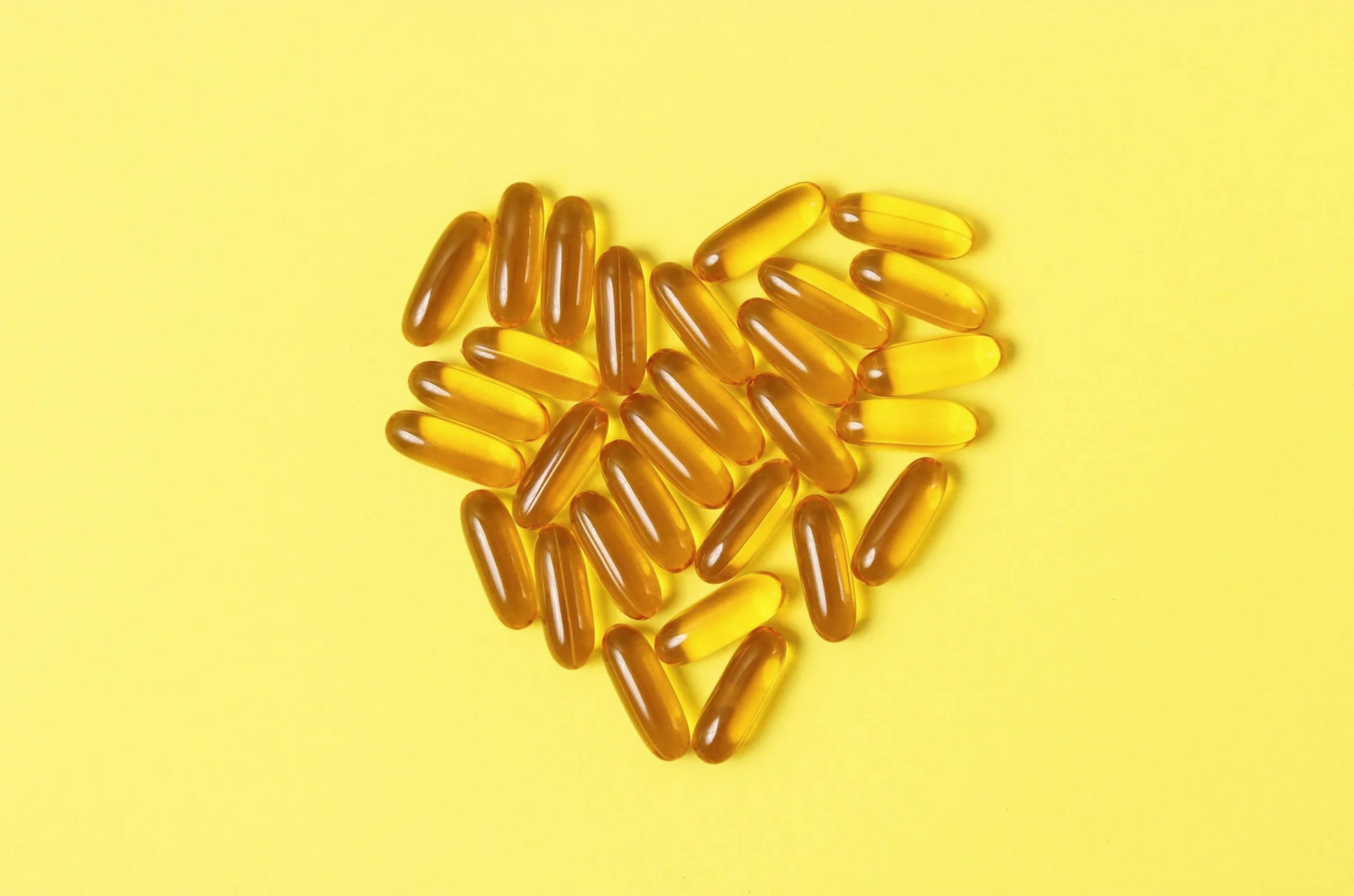 ACGrace - Heart shaped fish oil capsules on a yellow background.