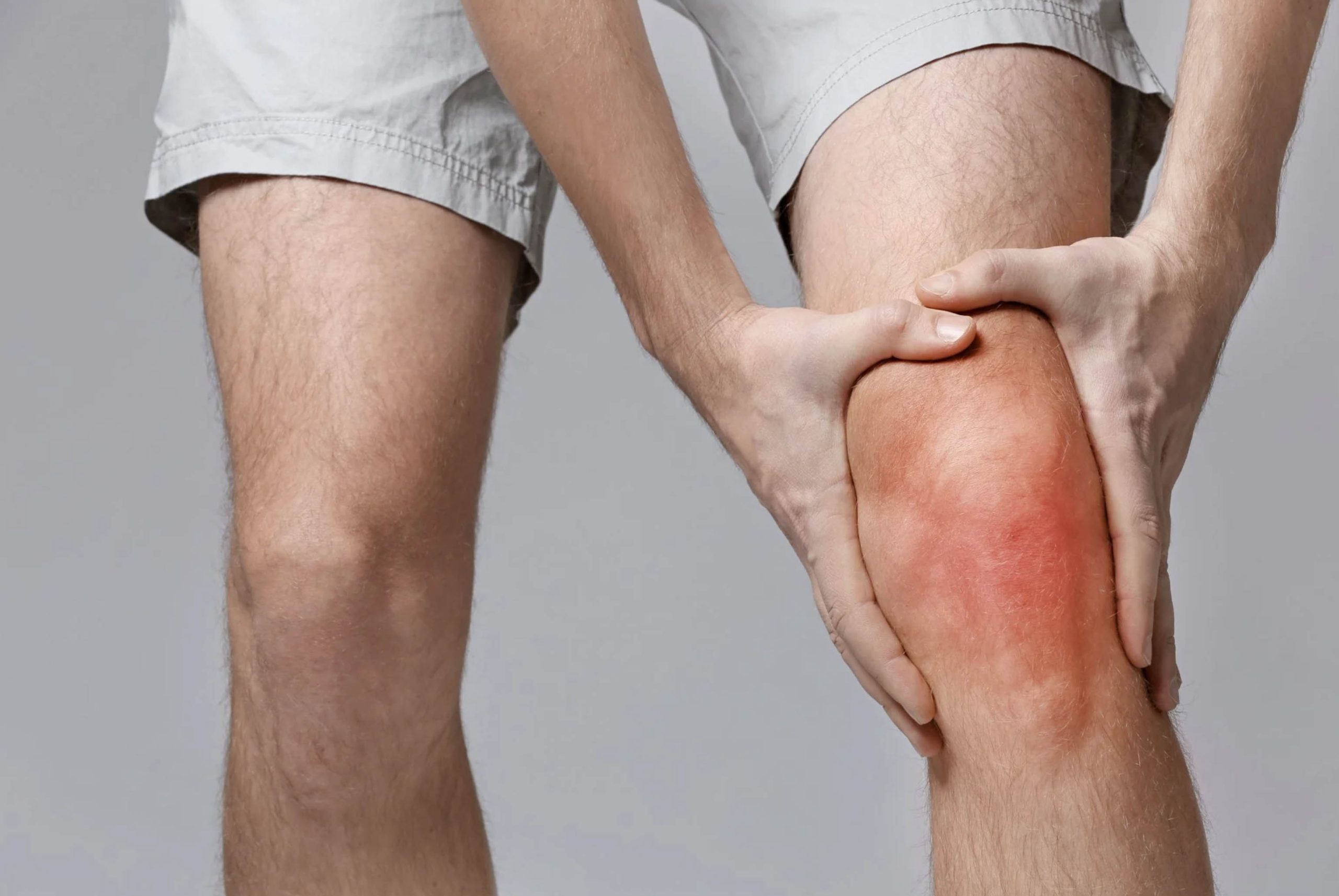 ACGrace - A man is holding his knee with pain.