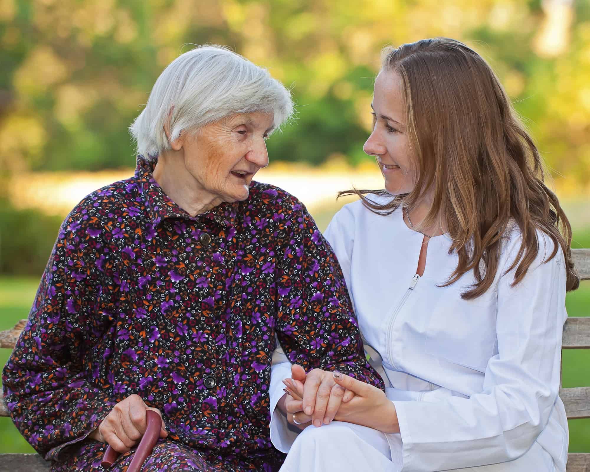 ACGrace - A woman talking to an older woman on a park bench.