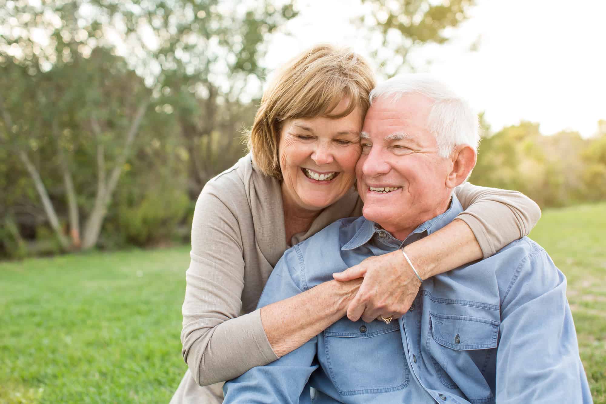 ACGrace - An elderly couple embracing and smiling outdoors.